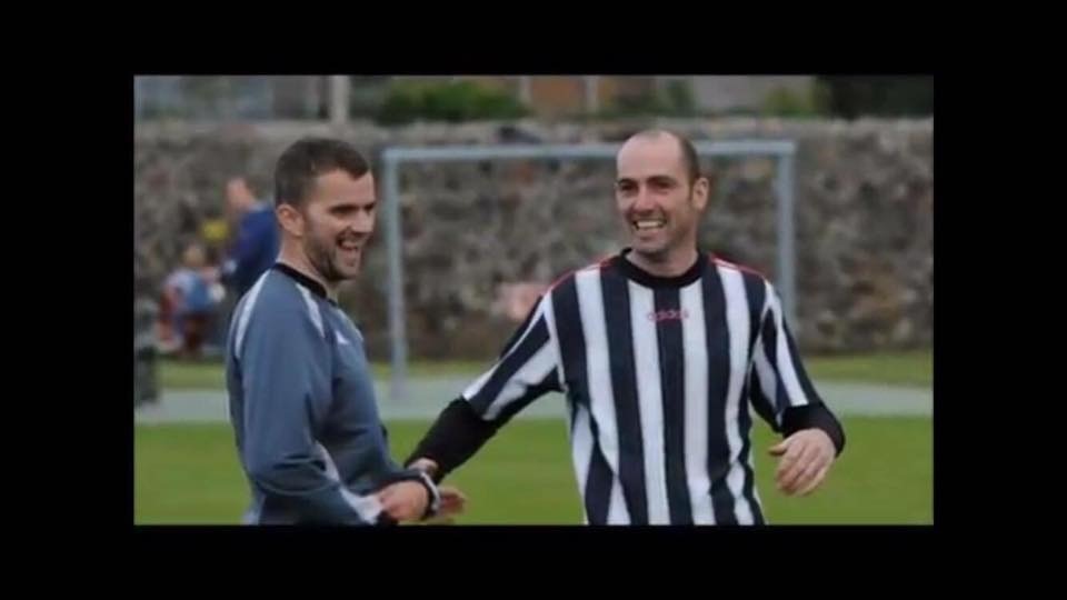 Alan Hyslop in a white and black striped kit on a football field.